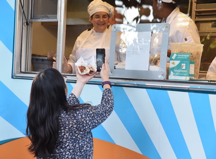 Food Trruck Student chef serves a woman with long dark hair.