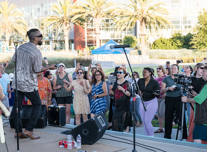 Singer entertains crowd at an outdoor event.