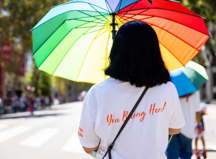 NoH8 Woman with shoulder-length black hair holds a rainbow umbrella at a Pride event for Mission College.