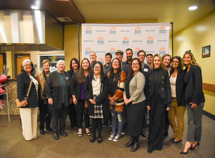 Group photo of Mission College staff, students, and community members in front of a branded backdrop.