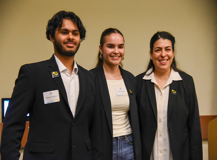 Three student ambassadors wearing Mission College 50th anniversary pins and posing together.
