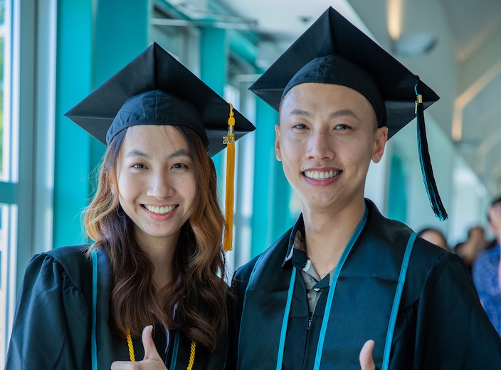 Programs APIA Scholarships Young Asian man and woman smile wearing commencement cap and gown.