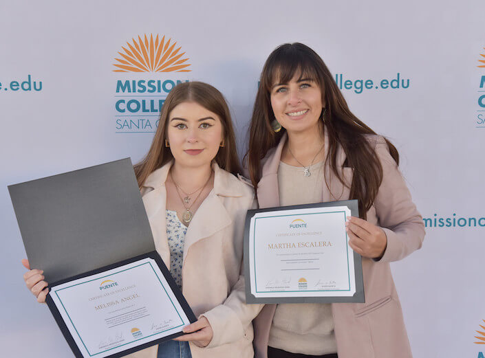 Puente Two female Puente graduates holding certificates at a commencement ceremony for PUENTE.