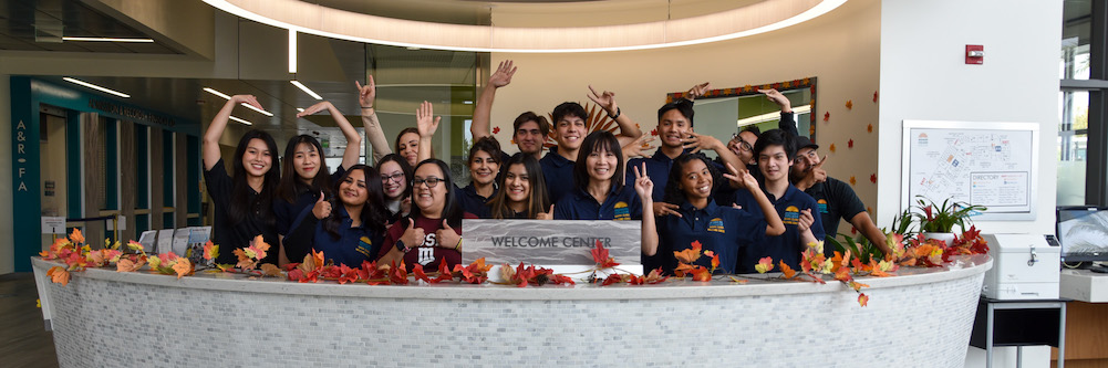 Welcome Center team in front of "Mission Sign" on campus.