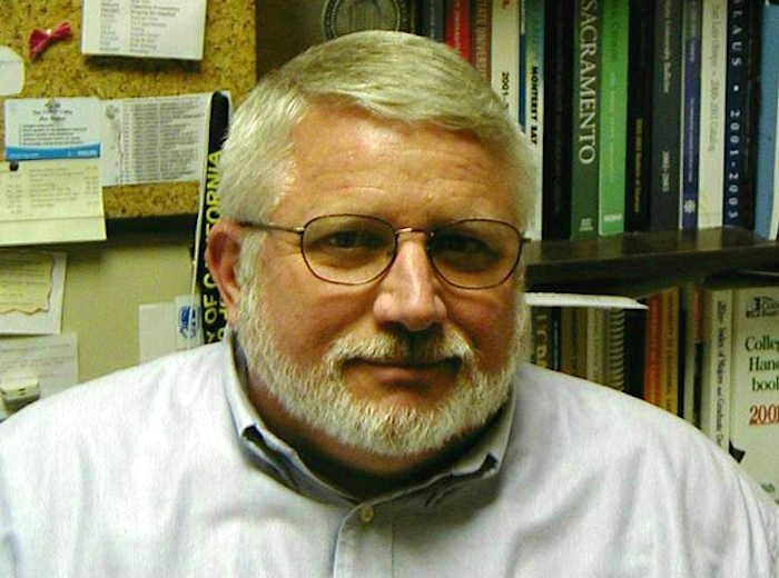 Bob Miller in office. He is an older white man with wireframe glasses, white hair, and a white beard. There is a bookshelf behind him.